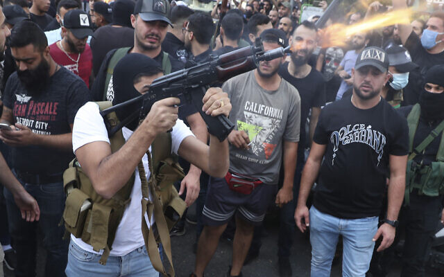 Supporters of the Shi'ite Amal group fire weapons in the air during the funeral processions of Hassan Jamil Nehmeh, who was killed during yesterday clashes, in the southern Beirut suburb of Dahiyeh, Lebanon, on Friday, October 15, 2021. (AP/Bilal Hussein)