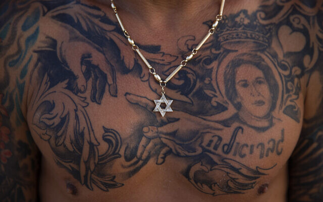 An Israeli beach worker wears a necklace with the Star of David pendant poses for a photo on the beachfront early morning in Tel Aviv, Israel, July 2, 2021. (AP Photo/Oded Balilty)