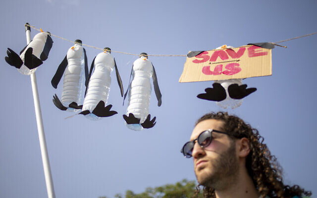 A man holds a display depicting dead penguins during a march demanding the world leaders to take action in reversing climate change and stop the use of fossil fuels in Tel Aviv, October 29, 2021. (AP Photo/Ariel Schalit)
