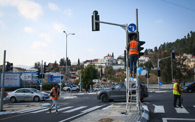 Illustrative: Workers operate a traffic light in the northern Israeli city of Tzfat, January 14, 2020. (David Cohen/Flash90)
