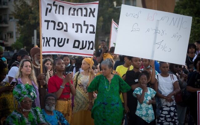 Members of the Hebrew Israelites Community of the southern city of Dimona protest against deportation orders given to some of their members, Habima Square, Tel Aviv, June 1, 2021. Th banner says, 'We are an integral part of the People of Israel.'  (Miriam Alster/Flash90)