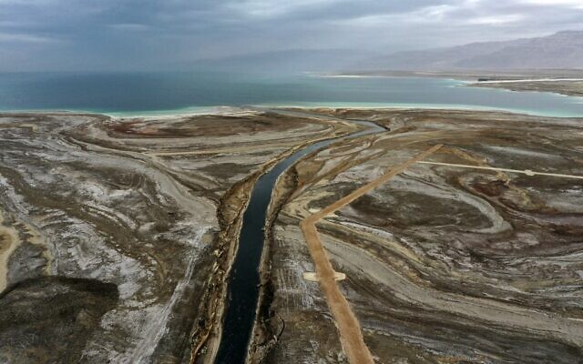 A picture taken in the area of Ein Gedi shows the Araba River crossing a dried-up sea stretch which exposed and created a salt plain, on its way to the southern part of Dead Sea, January 15, 2021. (Menahem KAHANA / AFP)