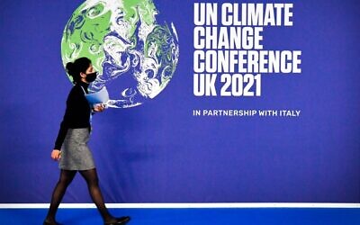 A participant walks past a COP26 UN Climate Change Conference' poster on the first day of the COP26 UN Climate Change Conference at the Scottish Event Campus (SEC) in Glasgow, Scotland, on October 31, 2021. (ALAIN JOCARD / AFP)