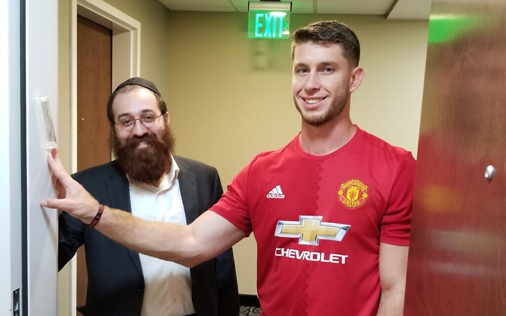NFL kicker Greg Joseph with Rabbi Yossi Friedman of the Chabad of Downtown Cleveland in 2018, standing by the mezuzah that Friedman helped Joseph put up outside his apartment. (Glen Joseph/ via JTA)