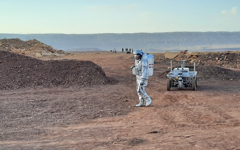 An Israeli analog astronaut walks inside a simulated spacesuit next to a space rover in the Ramon Crater in the Negev on October 31, 2021. (Amy Spiro)