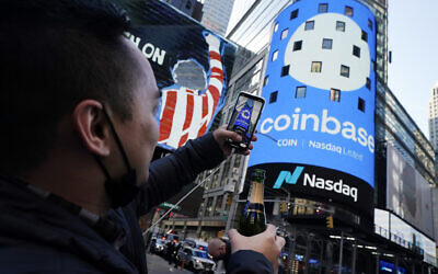 Coinbase employee Daniel Huynh holds a celebratory bottle of champagne as he photographs outside the Nasdaq MarketSite, in New York's Times Square, Wednesday, on April 14, 2021. (AP/Richard Drew)
