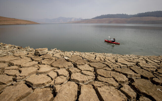 A kayaker fishes in Lake Oroville as water levels remain low due to continuing drought conditions in Oroville, Calif., Aug. 22, 2021. (AP Photo/Ethan Swope)