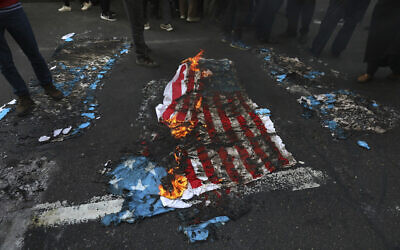 Mock US and Israeli flags are set on fire by demonstrators in a rally in front of the former US Embassy commemorating the anniversary of its 1979 seizure in Tehran, Iran, November 4, 2021. (AP Photo/Vahid Salemi)