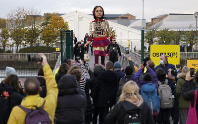 Little Amal, a 3.5m puppet of a 10-year-old Syrian refugee, crosses the Millennium Bridge near the venue of the COP26 UN Climate Summit in Glasgow, Scotland, November 9, 2021. (Alberto Pezzali/AP)