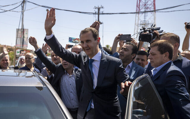 Syrian President Bashar Assad, right, waves to his supporters at a polling station during the presidential elections in the town of Douma, in the eastern Ghouta region, near the Syrian capital Damascus, Syria, May 26, 2021. (AP Photo/Hassan Ammar, File)