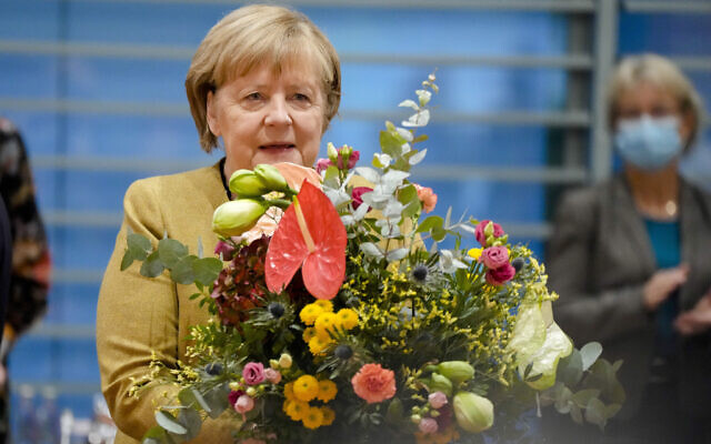 German Chancellor Angela Merkel holds a bouquet from Vice Chancellor and Finance Minister Olaf, Scholz prior to the cabinet meeting at the chancellery in Berlin, Germany, on November 24, 2021. (AP Photo/Markus Schreiber, Pool)