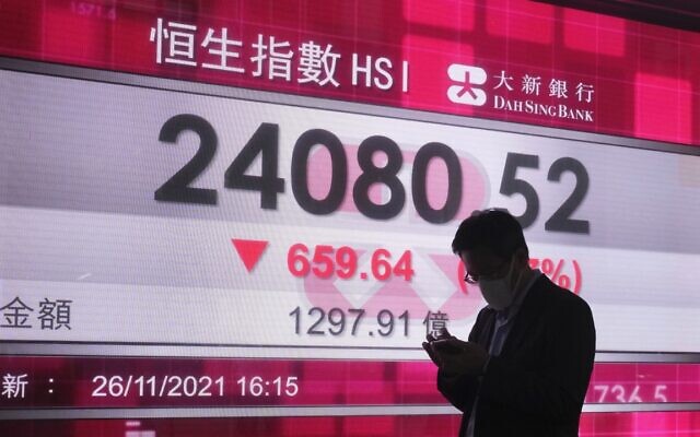 A man walks past a bank's electronic board showing the Hong Kong share index in Hong Kong, Friday, Nov. 26, 2021 (AP Photo/Kin Cheung)