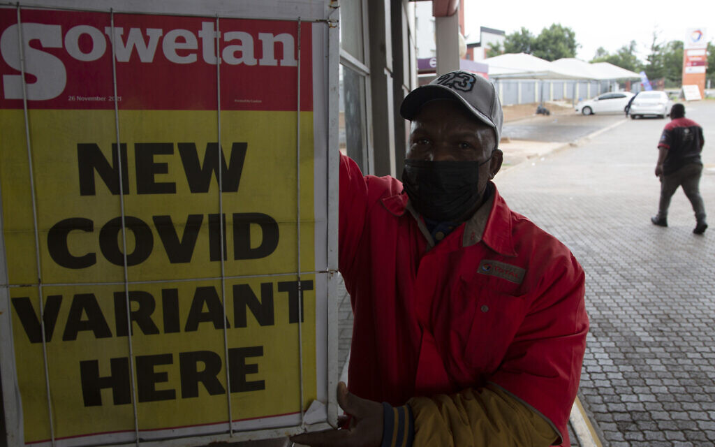A petrol attendant stands next to a newspaper headline in Pretoria, South Africa, November 27, 2021. (AP Photo/ Denis Farrell)