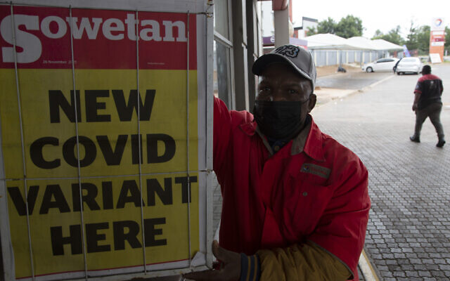 A gas station attendant stands next to a newspaper headline in Pretoria, South Africa, Nov. 27, 2021. (Denis Farrell/AP)