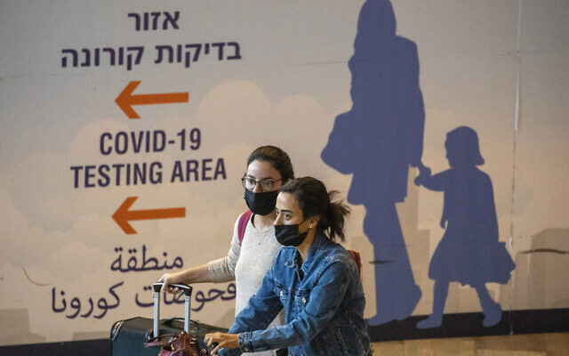 Travelers wearing protective face masks arrive at Ben Gurion Airport near Tel Aviv, Israel, November 28, 2021. (AP Photo/Ariel Schalit)