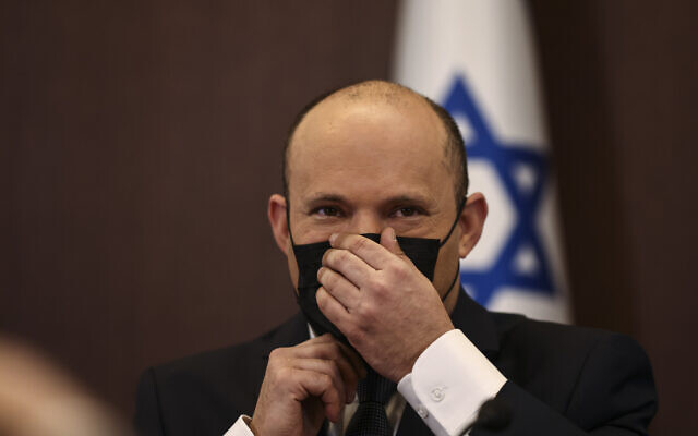 Prime Minister Naftali Bennett adjusts his mask at a cabinet meeting at the Prime Minister's office in Jerusalem, November 28, 2021. (Ronen Zvulun/Pool via AP)