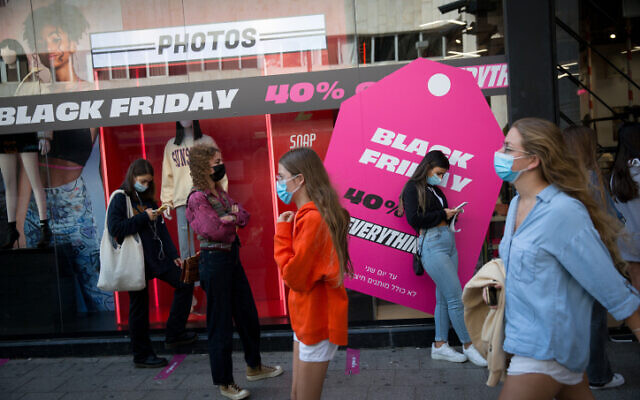 People stand outside a clothing shop advertising Black Friday sales in Tel Aviv, on November 25, 2020 (Miriam Alster/FLASH90)