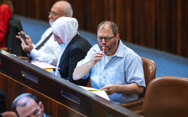 Joint List MK Ofer Cassif eats a lollipop in the Knesset in Jerusalem on November 3, 2021. (Olivier Fitoussi/Flash90)