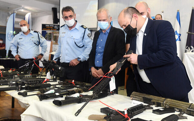 Prime Minister Naftali Bennett (R) inspect illegal firearms seized by police, at a ceremony in Tel Aviv, November 9, 2021. (Haim Zach/GPO)