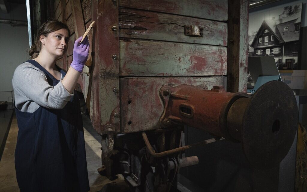 Preservation technician Emily Thomas cleans a rail wagon of the type used to transport victims to death camps at the Holocaust Gallery at the Imperial War Museum in London, September 30, 2021. (Courtesy of the Imperial War Museum)