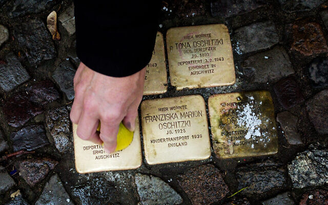 A local resident polishes a so-called 'Stolpersteine' or 'stumbling stones' commemorating people deported and killed by the Nazis in front of his house in Berlin, Germany, Nov. 9, 2021, the 83th anniversary of the Nazis' anti-Jewish Kristallnacht pogrom in 1938. (AP Photo/Markus Schreiber)