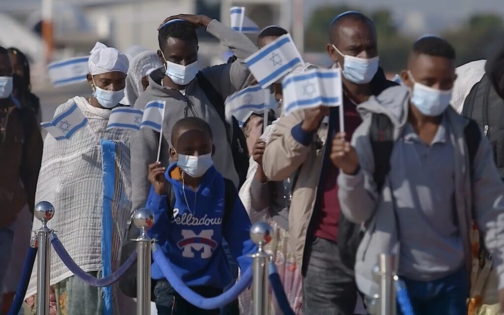 Ethiopian Jews arrive in Israel waving Israeli flags in this still from the documentary 'With No Land.' (Courtesy of the Other Israel Film Festival)
