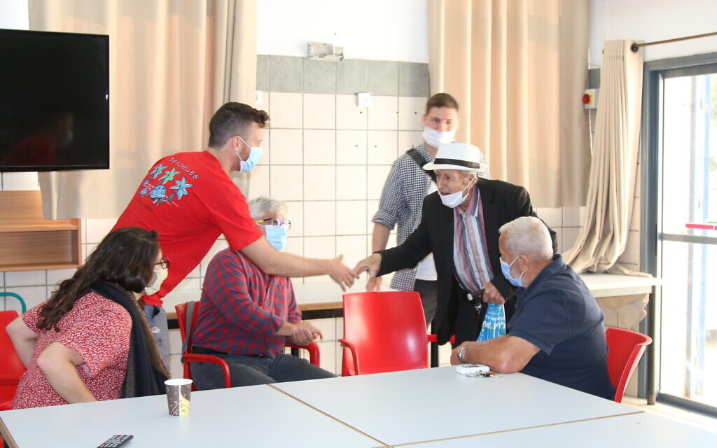 Blend.ar participants speak with older men at the community center in Abu Ghosh, October 2021. (Shmuel Bar-Am)