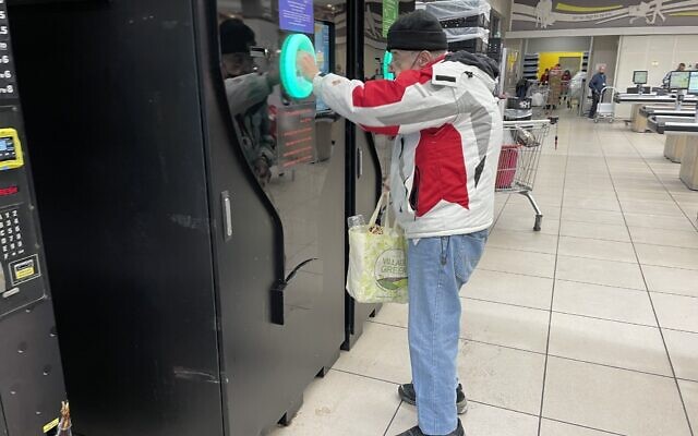 A shopper tries out the bottle deposit automat at a Talpiot, south Jerusalem, branch of the Yochananoff supermarket chain, November 23, 2021. (Sue Surkes/Times of Israel)
