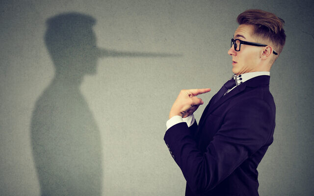 A man in pointing at himself looking at shadow with long nose of a liar (iStock via Getty Images)
