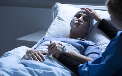 Volunteer supporting woman dying of tumor in a hospital room. (iStock photo)