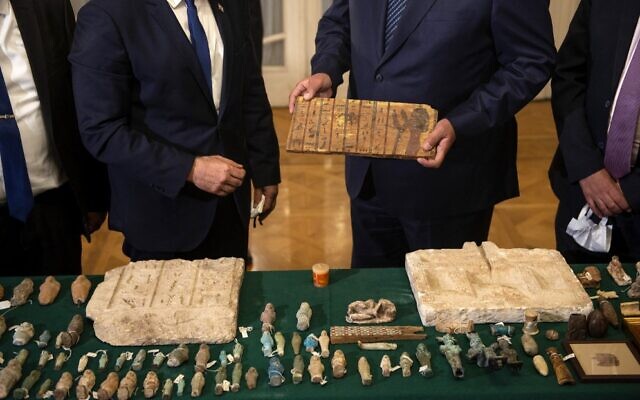 Foreign Minister Yair Lapid (L) presents Egypt's Foreign Minister Sameh Shoukry (R) with stolen Egyptian artifacts that were smuggled to Israel and returned back to Egypt, during their meeting at Tahrir Palace in Cairo on December 9, 2021. (Mohamed HOSSAM / AFP)