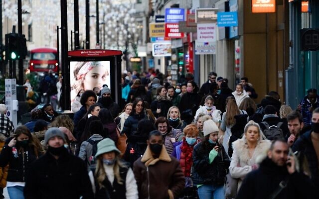 Shoppers, some wearing face coverings to combat the spread of COVID-19, walk along Oxford Street in central London, on December 10, 2021. (Niklas Halle'n/AFP)