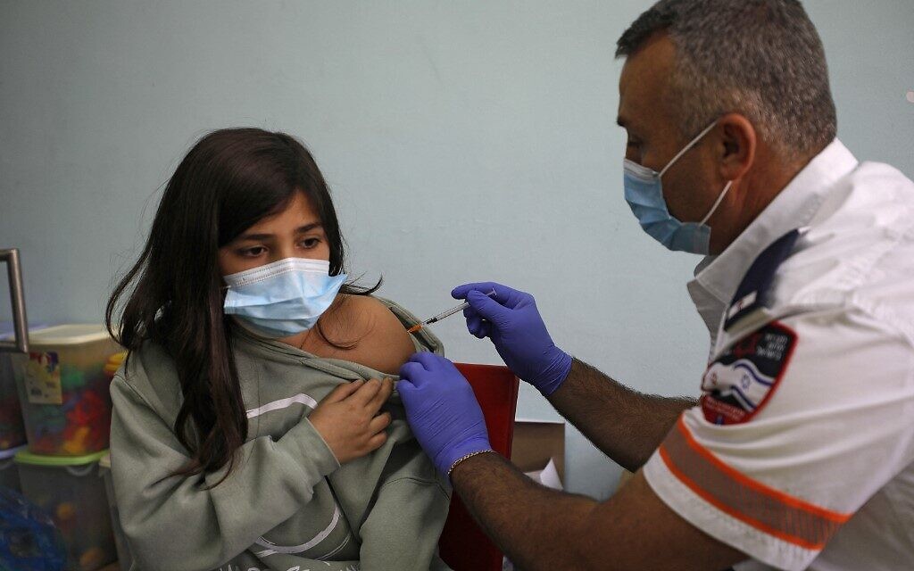 An Israeli health worker administers a dose of the Pfizer/BioNTech COVID-19 vaccine to a student at the al-Manahel School in the village of Majdal Shams on December 12, 2021. (JALAA MAREY / AFP)