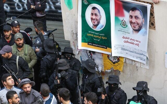 Armed fighters and people take part in a funeral procession for Hamza Ibrahim Shahin (pictured in posters), a member of the Gaza-ruling Hamas terror group, in the Burj al-Shamali camp for Palestinian refugees near the southern Lebanese coastal city of Tyre on December 12, 2021. (Mahmoud Zayyat/AFP)