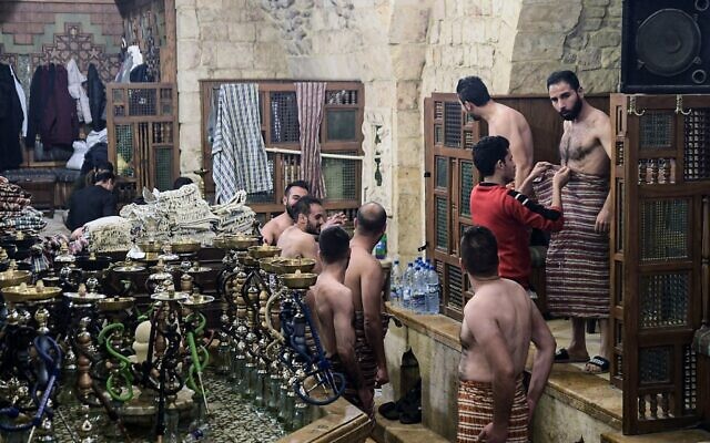 Men dry up after bathing at Hammam al-Qawas, a traditional Turkish bathhouse, in Syria's northern city of Aleppo on December 16, 2021. (Photo by AFP)