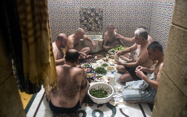 Men eat lunch after bathing at Hammam al-Qawas, a traditional Turkish bathhouse, in Syria's northern city of Aleppo on December 16, 2021. (Photo by AFP)