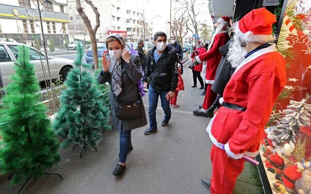 A man dressed as Santa greets Iranians as they walk past a shop selling Christmas decorations in the capital Tehran on December 24, 2021. (AFP)