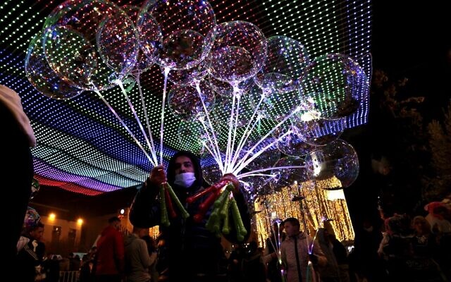 Vendors sell balloons to visitors in Manger Square on Christmas eve outside the Church of the Nativity, revered as the site of Jesus Christ's birth, in the biblical city of Bethlehem in the West Bank on December 24, 2021. (ABBAS MOMANI / AFP)