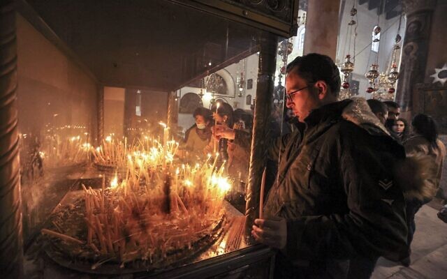 Milad Ayyad, a Palestinian Greek Orthodox Christian from Gaza, lights candles at the Greek Basilica at the Church of the Nativity, the traditional place of Christ's birth, in the biblical city of Bethlehem in the occupied West Bank, on December 26, 2021. (Hazem Bader/AFP)