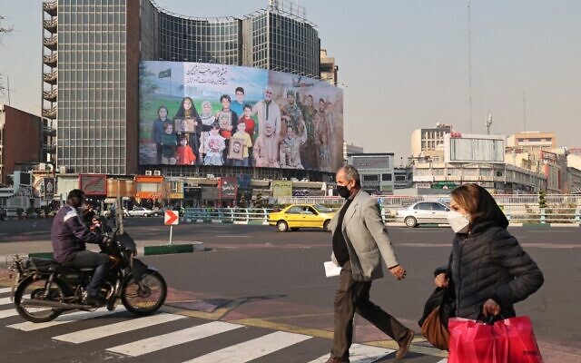 Iranians cross a street, next to a poster of slain top Iranian commander Qasem Soleimani and slain Iraqi commander Abu Mahdi al-Muhandis, in the capital Tehran on December 28, 2021. (ATTA KENARE / AFP)