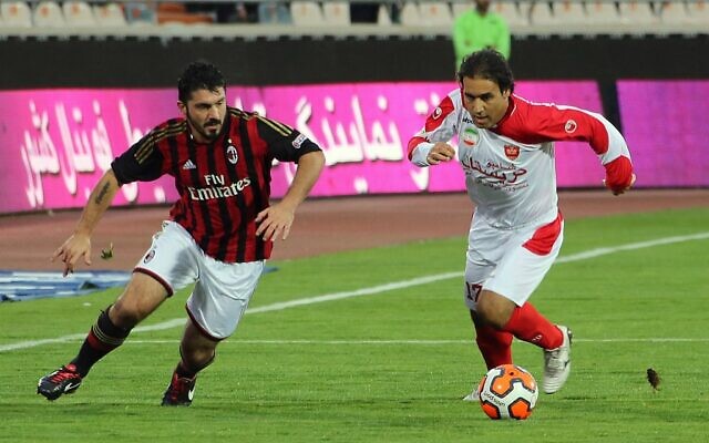 This file photo taken on November 28, 2013, shows former former Persepolis player Mehdi Mahdavikia (R) and former AC Milan player Gennaro Gattuso vying for the ball during an exhibition soccer match at the Azadi stadium in Tehran. (Photo by ATTA KENARE / AFP)