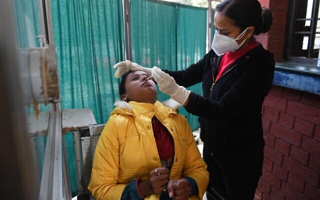 A health worker collects a nasal swab sample from a woman to test for COVID-19 at a hospital in Amritsar on December 31, 2021. (Narinder Nanu/AFP)