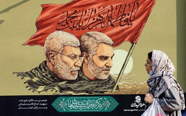 An Iranian woman walks past a large poster of slain top Iranian general Qasem Soleimani (R) and senior Hashed commander Abu Mahdi al-Muhandis ahead of the second anniversary of their death, in the capital Tehran, on December 31, 2021. (AFP)