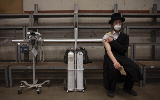 A man rests after receiving his second dose of the Pfizer COVID-19 vaccine at a coronavirus vaccination center set up at a synagogue in Bnei Brak, Israel, March. 7, 2021. (AP Photo/Oded Balilty)