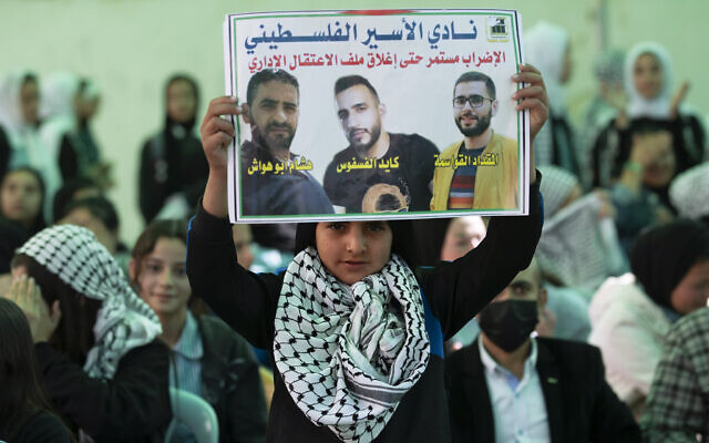 Protesters carry posters showing Kayed Fasfous, a Palestinian prisoner who has been on hunger strike for 120 days to protest being detained without charge by Israel, in the village of ad-Dhahiriya, near Hebron, Thursday, Nov. 11, 2021. (AP Photo/Majdi Mohammed)