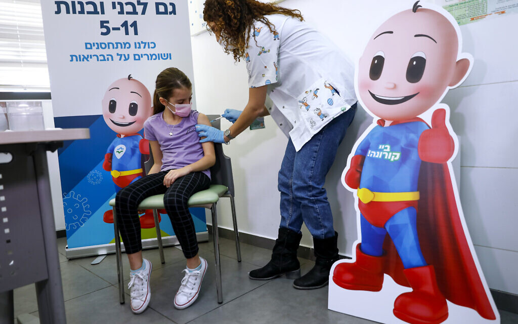 An Israeli girl receives her first Pfizer-BioNTech COVID-19 vaccine from medical staff at Clalit Health services in Tel Aviv, on Tuesday, Nov. 23, 2021. (AP Photo/Oded Balilty)