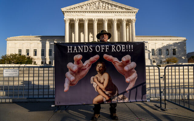 A protester holds a sign that reads 'Hands Off Roe!!!' outside of the US Supreme Court ahead of arguments in case at the court challenging abortion laws, seen in Washington, November 30, 2021. (Andrew Harnik/AP)