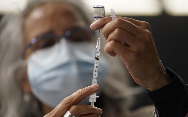 A doctor transfers Pfizer's COVID-19 vaccine into a syringe, December 2, 2021, at a mobile vaccination clinic in Worcester, Massachusetts. (AP Photo/Steven Senne)