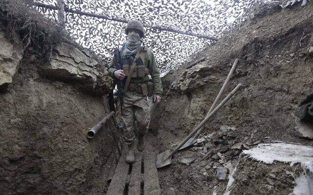 Ukrainian soldiers walks under a camouflage net in a trench on the line of separation from pro-Russian rebels near Debaltsevo, Donetsk region, Ukraine, Ukraine Friday, Dec 3, 2021 (AP Photo/Andriy Dubchak)
