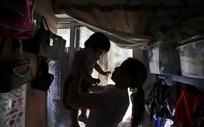 Maya, 36, plays with her one-year-old undocumented daughter in a dank, overstuffed section of an apartment, subdivided by hinged partitions, that she shares with eight other women, in Dubai, United Arab Emirates, Nov. 24, 2021.  (Kamran Jebreili/AP)